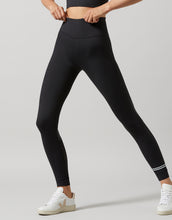 Person wearing black leggings with white sneakers on a light gray background