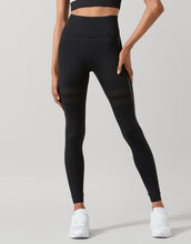 Person wearing black leggings with a plain background