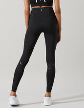 Person wearing black high-waisted leggings on a light gray background