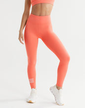 Person wearing coral leggings with white stripes on a light gray background