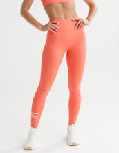 Person wearing coral leggings with white stripes on a light gray background