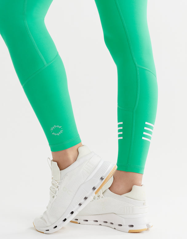 Close up of a womans legs wearing green leggings and white shoes