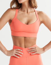Person wearing a coral sports bra and leggings on a white background