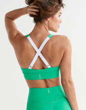 Woman wearing a green sports bra and leggings on a white background