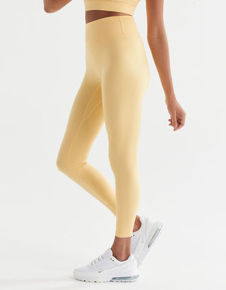 A pair of high-waisted yellow leggings with a minimal seaming design, designed for activewear with white sneakers.