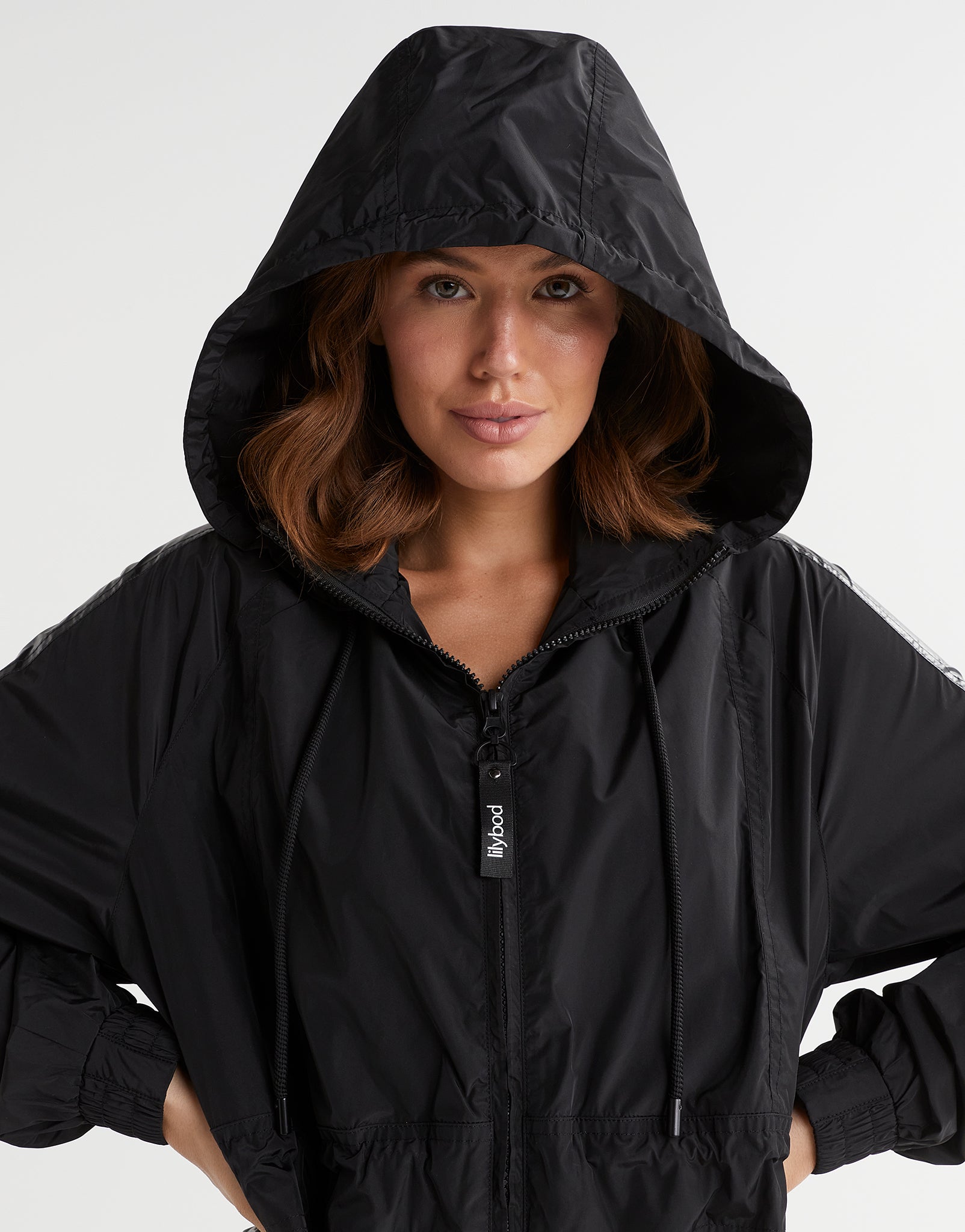 Person wearing a black hooded jacket on a white background