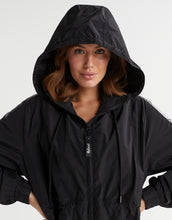 Person wearing a black hooded jacket on a white background