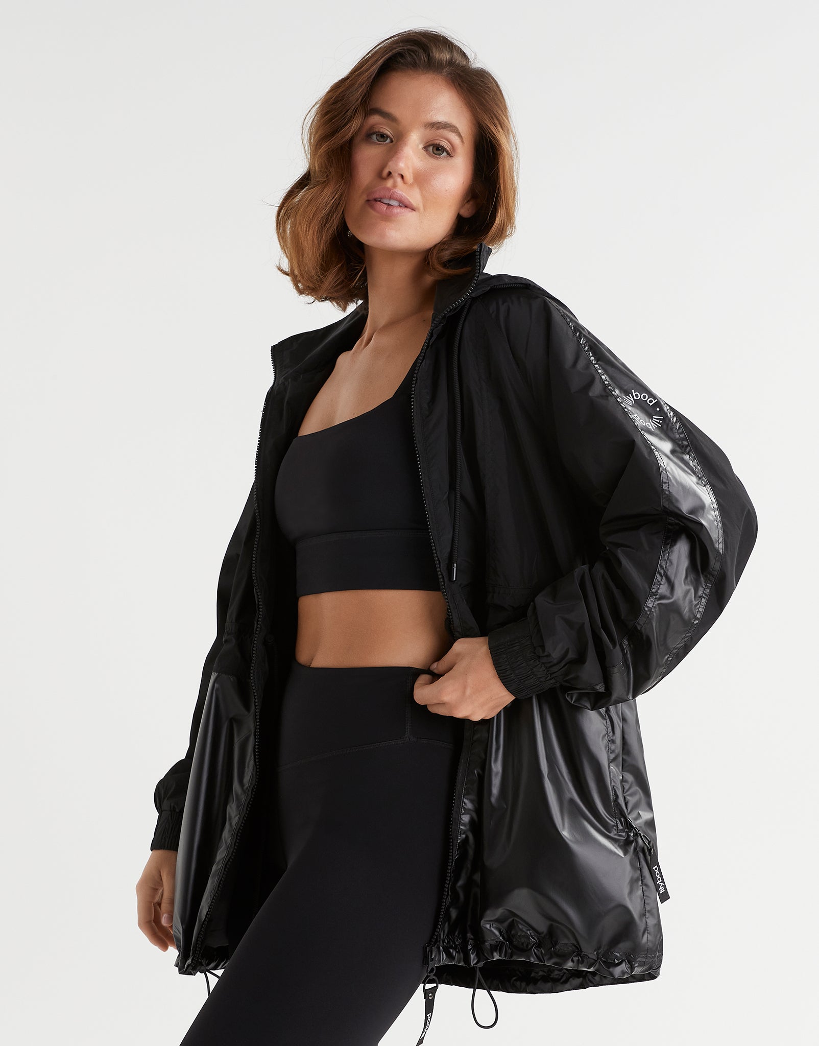 Woman wearing a black athletic outfit with a jacket on a white background