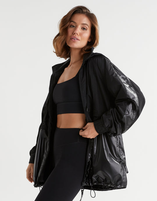 Woman wearing a black athletic outfit with a jacket on a white background