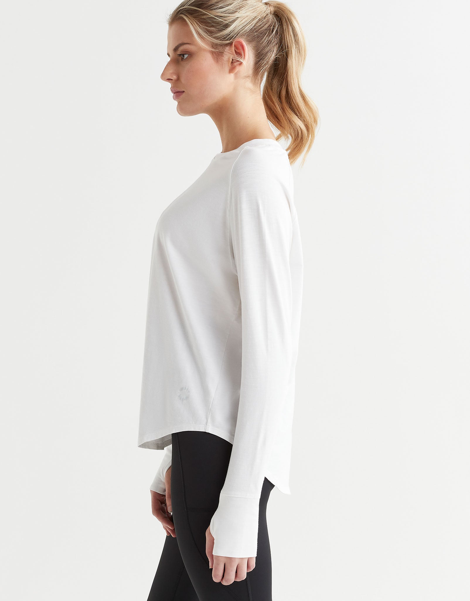 A female wearing a long-sleeved white t-shirt with a round neckline, paired with black leggings