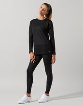 Woman wearing a black long-sleeve top and leggings on a gray background