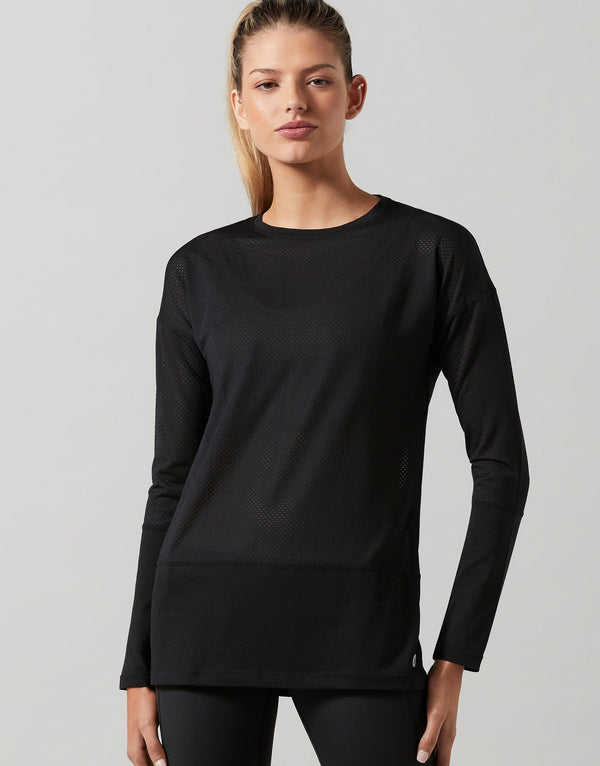 Woman wearing a black long-sleeve athletic top on a gray background