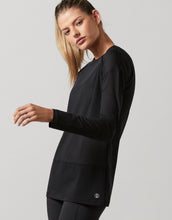 Woman wearing a black long-sleeve athletic top on a gray background