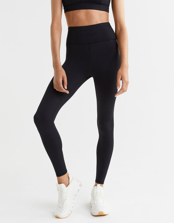 Person wearing black leggings and white sneakers on a white background