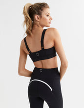 Woman wearing a black sports bra and leggings on a white background