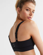 Woman wearing a black sports bra on a white background