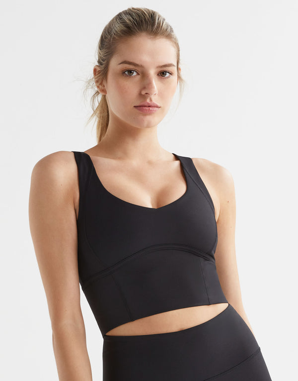 Woman wearing a black sports bra and leggings on a light gray background