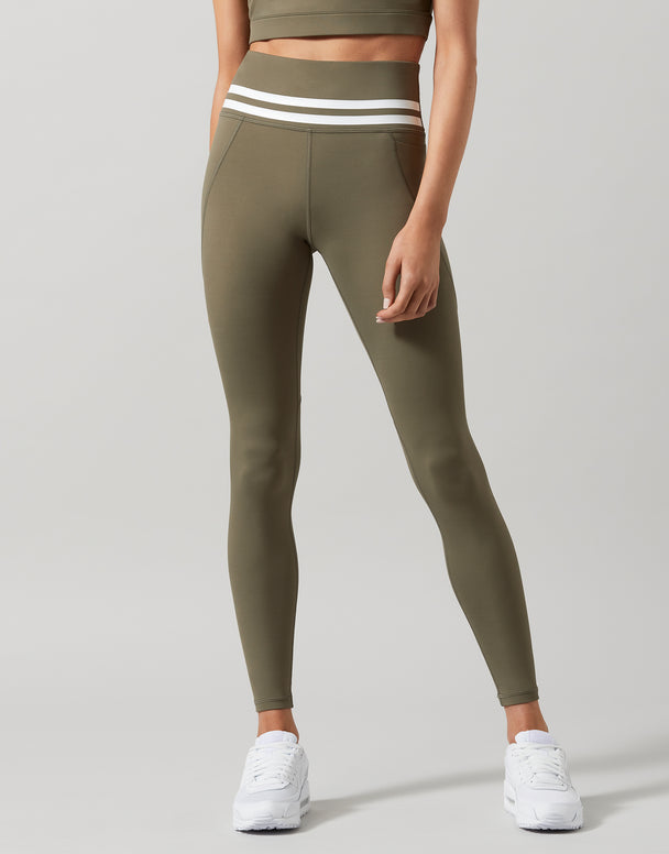 A pair of khaki green Lilybod Dakota leggings with a sports bra and white sneakers.
