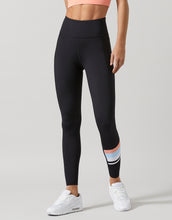 Person wearing black leggings with colorful accents on a gray background