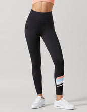 Black leggings with colorful stripe design worn by a person on a gray background