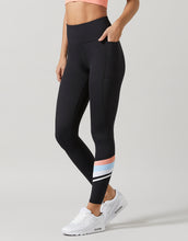 Person wearing black leggings with colorful stripes on a light gray background