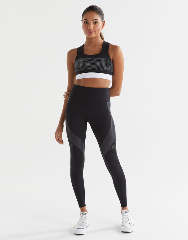 Woman wearing a black athletic outfit with a white background