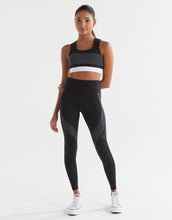 Woman wearing a black athletic outfit with a white background
