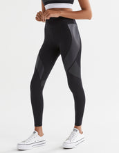 Person wearing black leggings with gray accents on a white background