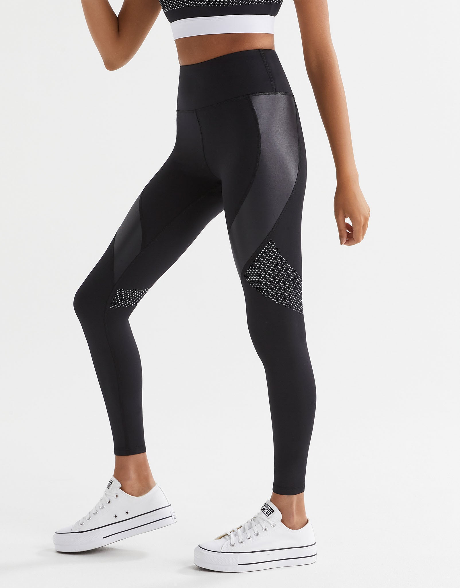 Black leggings with mesh panels worn by a person on a white background