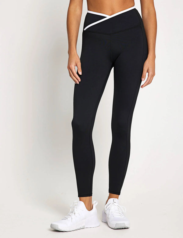 Person wearing black leggings with a white waistband on a light gray background