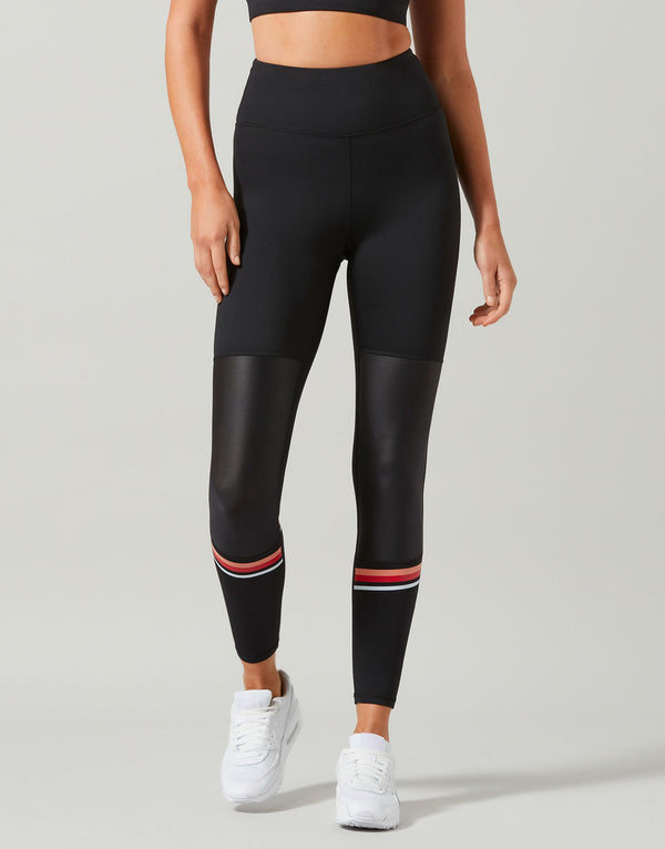 Person wearing black leggings with red accents on a gray background