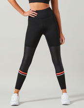 Person wearing black leggings with red and white accents on a gray background