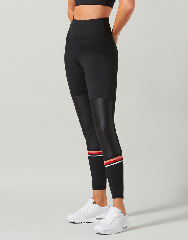 Person wearing black leggings with red and white stripes on a gray background