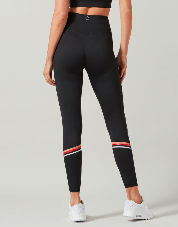 Black leggings with red and white accents worn by a person on a light gray background