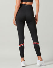 Black leggings with red and white accents worn by a person on a light gray background