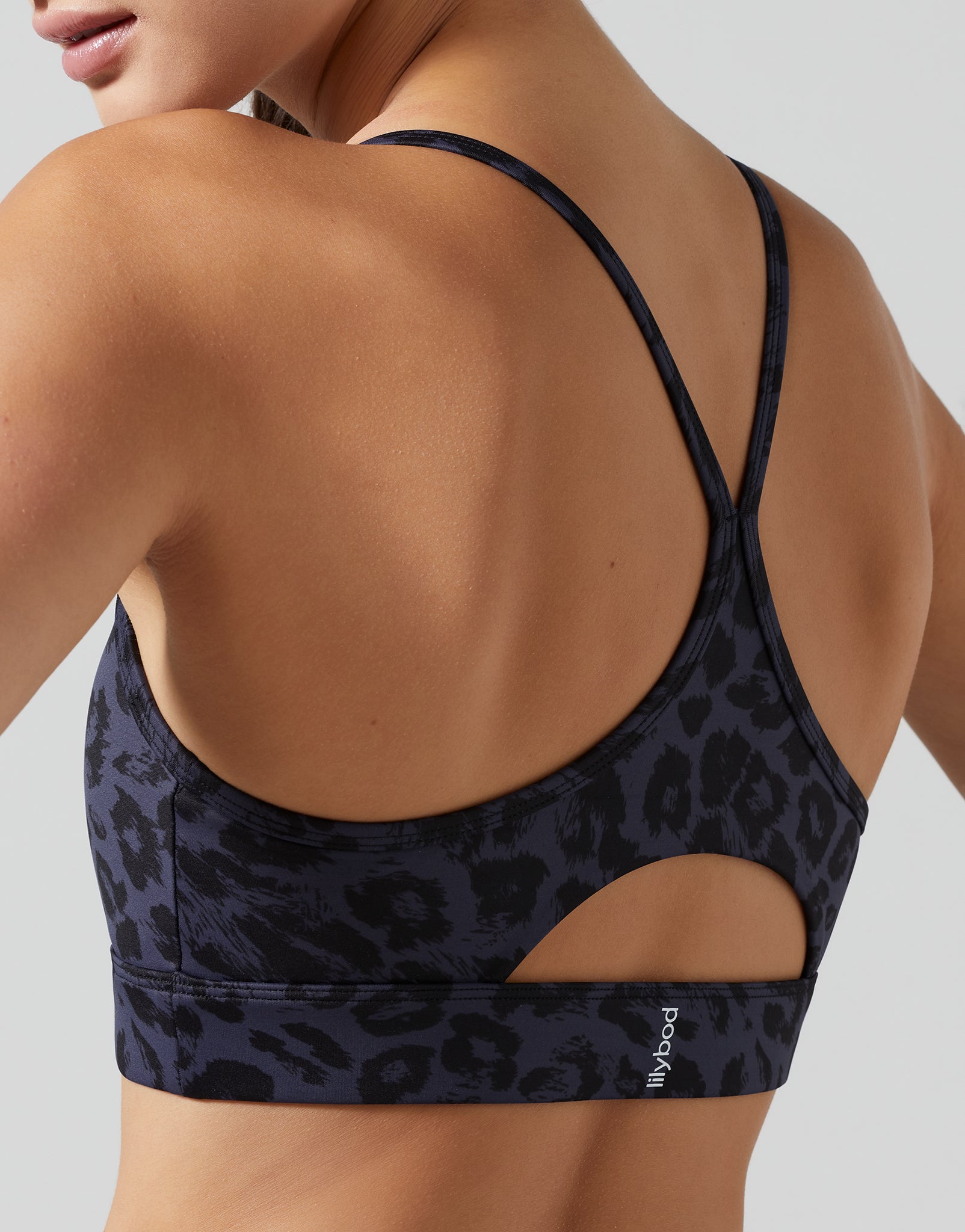 Black leopard print sports bra worn by a person on a light gray background