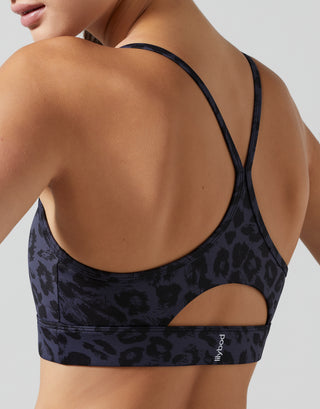 Black leopard print sports bra worn by a person on a light gray background