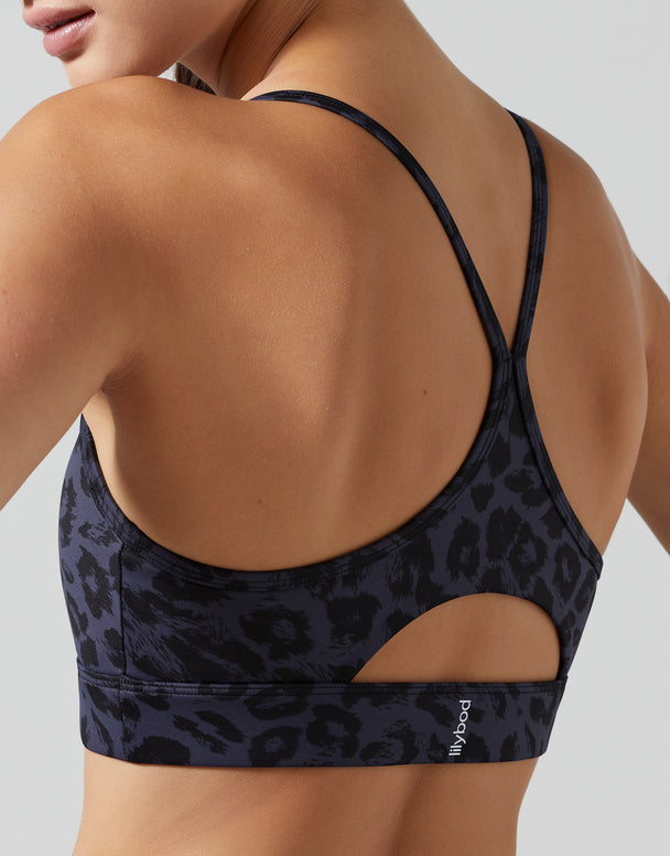 Black leopard print sports bra worn by a person on a light gray background