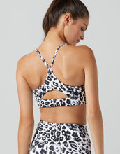 Woman wearing a leopard print sports bra and shorts on a plain background