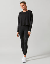 Woman wearing a black long-sleeve top and leggings on a gray background