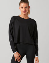 Woman wearing a black long-sleeve top and leggings on a gray background