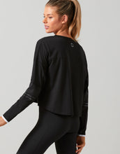 Woman wearing a black long-sleeve top and leggings on a gray background