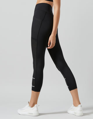 Person wearing black leggings with white accents on a light gray background