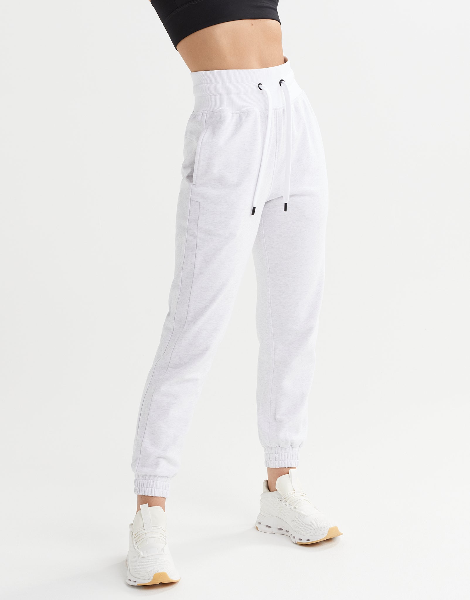 White jogger pants worn by a person on a white background