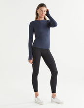 Woman wearing a navy long-sleeve top and black leggings on a white background