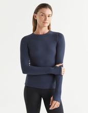 Woman wearing a navy long-sleeve top against a light gray background