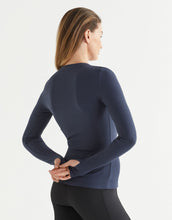 Woman wearing a blue long-sleeve athletic top on a light gray background