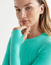 Woman wearing a teal ribbed sweater against a light background