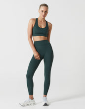 Woman wearing a green sports bra and leggings set on a white background