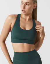 Woman wearing a green sports bra and leggings on a white background